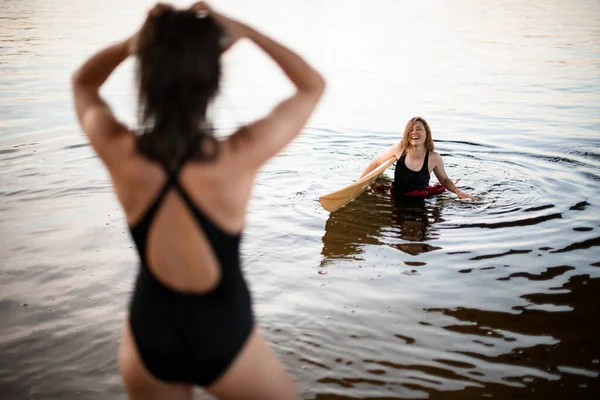 Jeune femme souriante avec planche de surf sort de l'eau — Photo