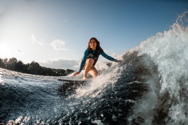 smiling young woman wakesurfing down the river waves clipart