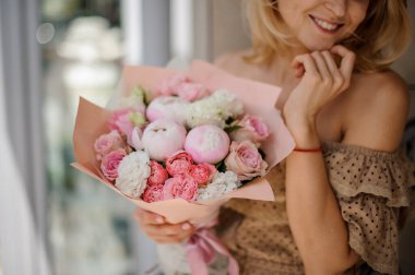 Tatlı yumuşak şakayık buketi pastel pembe renkli kadınların ellerinde.