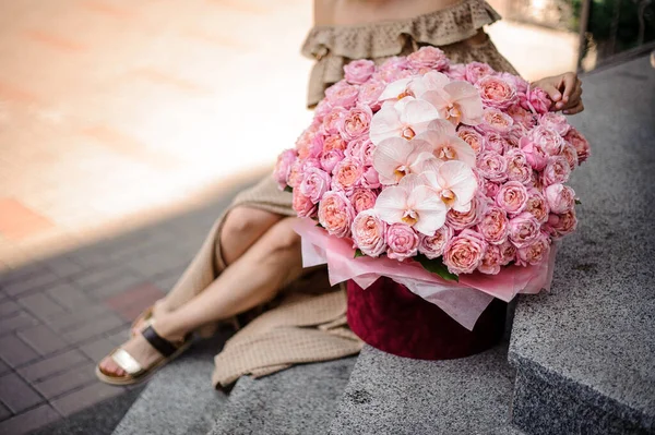 Великий букет з рожевих троянд і орхідей в червоній круглої коробці стоїть на сходах . — стокове фото