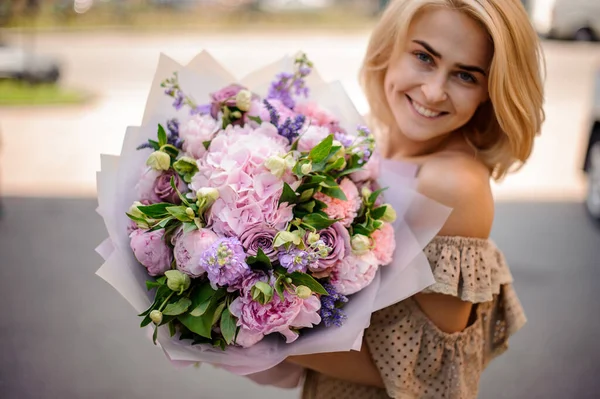 Jeune femme souriante tient bouquet tendre de fleurs — Photo