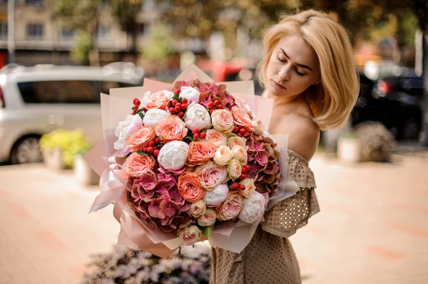 Молода жінка тримає букет з півоній, гортензії, троянд і червоних ягід . — стокове фото
