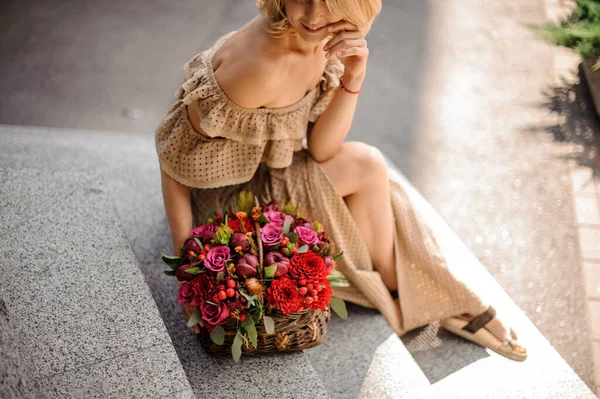 Vista de alto ângulo da mulher com cesta pequena cheia de flores vermelhas frescas . — Fotografia de Stock