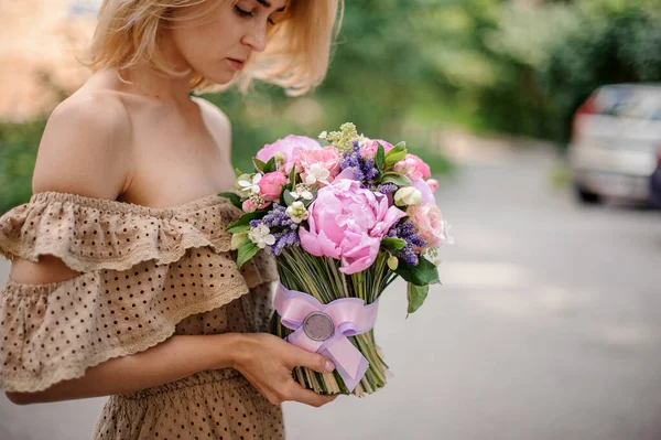 Giovane donna bionda tiene in mano delicato bouquet decorato con nastro di raso — Foto Stock