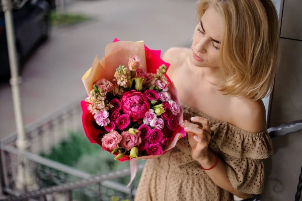 Ung vacker kvinna innehar bukett med ljusa bukett av färska rosor och andra blommor — Stockfoto