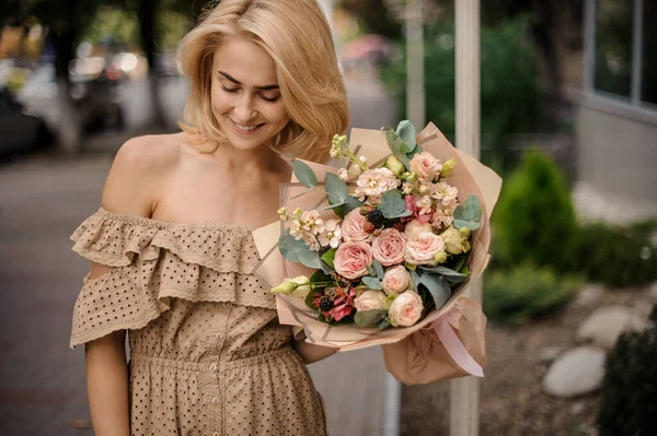 Giovane bella donna tiene bouquet di rose crema con foglie di eucalipto e more. — Foto Stock