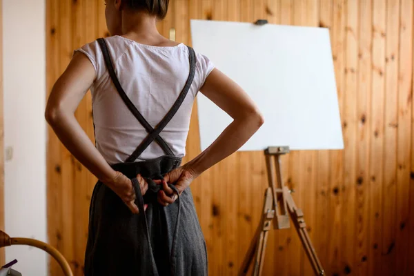 Rear view of young woman artist who is tying gray apron — Stock Photo, Image