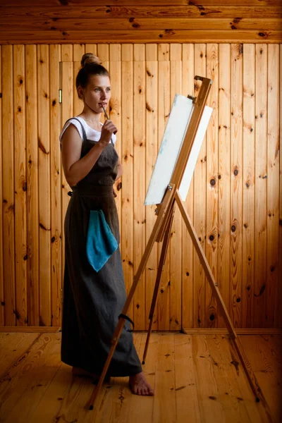 Красива молода жінка художник стоїть біля мольберта — стокове фото