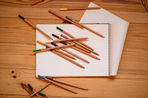 색연필 과 나무 탁자 위의 스케치 책 — 스톡 사진