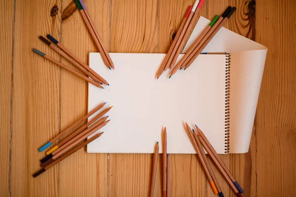 명확 한 스케치북 위에는 여러 가지 색상 연필이 놓여 있다 — 스톡 사진