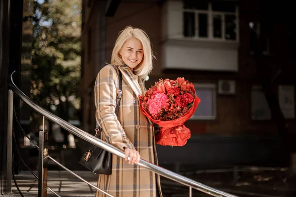Wanita tersenyum memegang dalam karangan bunga tangannya warna merah cerah — Stok Foto