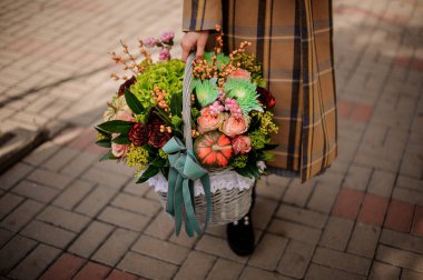 Hasır sepete yakın plan, çiçek aranjmanı da kadınların elinde..
