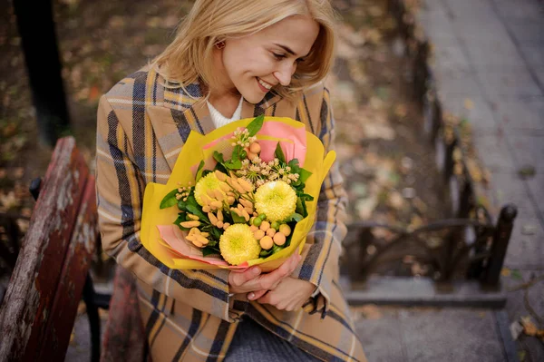 Mulher segura ordenadamente em suas mãos buquê de flores amarelas — Fotografia de Stock