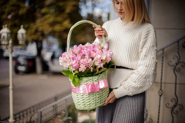 Woman holds basket with pink ribbon and pink flowers inside — Stock Photo, Image