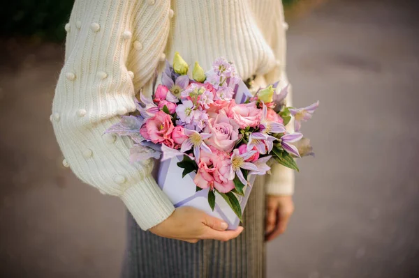 Finom virágkötészet négyzet alakú dobozban, női kézben. — Stock Fotó