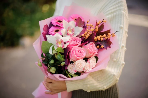 Close-up de buquê com rosas, gerbera, orquídeas e bagas nas mãos da mulher . — Fotografia de Stock