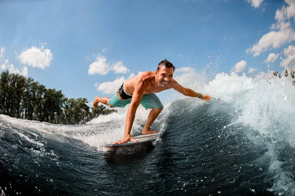 Wakesurfer cavalca lungo l'onda e tocca lo spruzzo d'acqua con la mano — Foto Stock