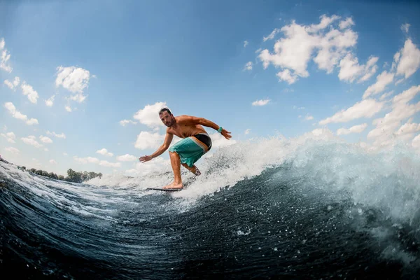 Atlético cara wakesurfer ativamente passeio no ondas no surf contra o céu azul — Fotografia de Stock