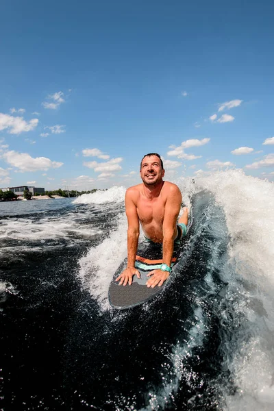 Pria dewasa tersenyum mengendarai gelombang sambil berbaring di papan selancar. — Stok Foto