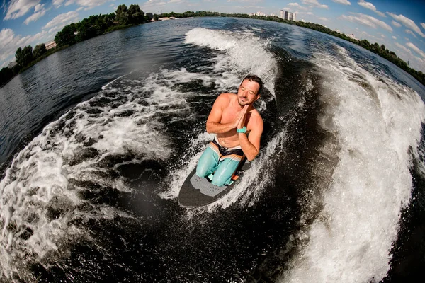 Hög vinkel syn på människan med slutna ögon och be pose på surfbrädet på vattnet — Stockfoto
