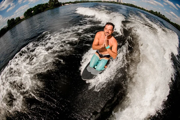 Vy över lycklig man i be pose som sitter på surfbrädet på vattnet — Stockfoto