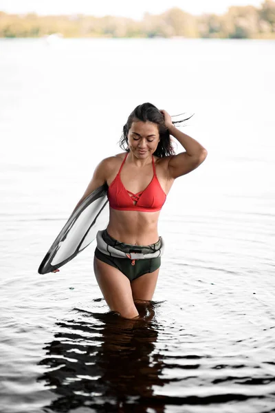 매력적 인 젊은 여자가 파도타기 판을 들고 물에서 나온다. — 스톡 사진