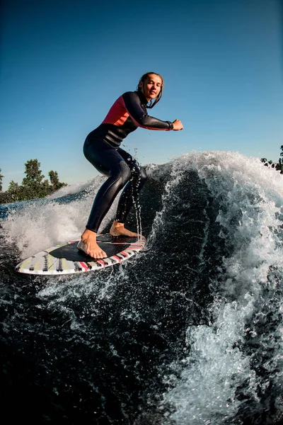 Nasse Sportlerin reitet auf Surfbrett gegen strahlend blauen Himmel die Welle hinunter — Stockfoto
