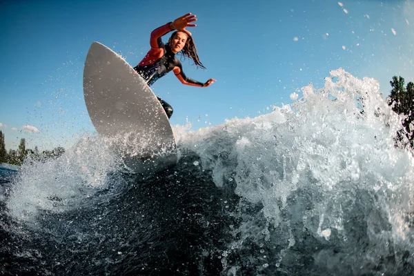 Mujer joven monta activamente la ola salpicada en la tabla de surf —  Fotos de Stock