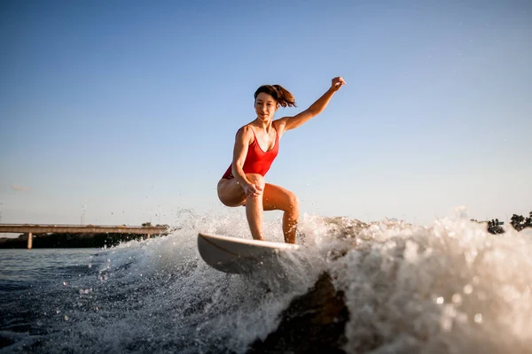 Sportliche Frau reitet auf der Welle auf Surfbrett — Stockfoto