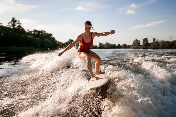 ハンサムな女性がボートから川の波に乗ってサーフボードに乗り — ストック写真