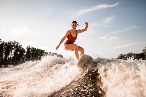 Mujer guapo efectivamente cabalga hacia abajo en la tabla de surf en la ola del río —  Fotos de Stock