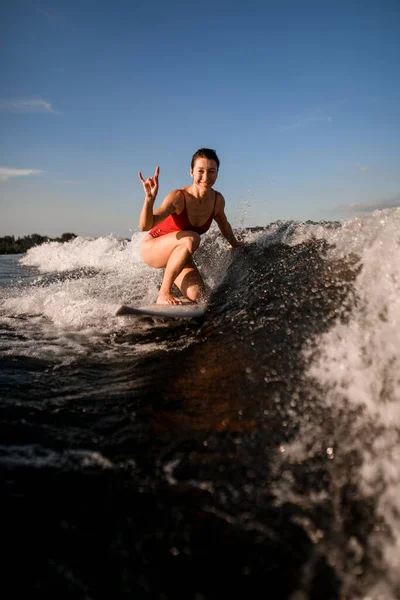 Donna sorridente cavalca sulla tavola da surf e mostra gesto della mano — Foto Stock