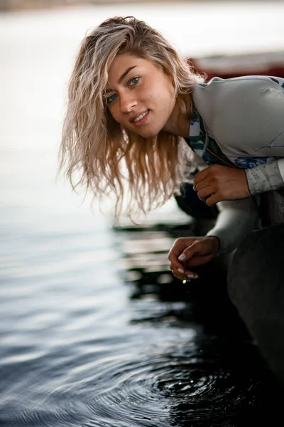 Ritratto di giovane bella donna bionda in costume da bagno che giace sul molo e raccoglie l'acqua — Foto Stock