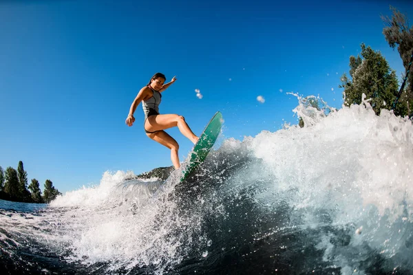 Joven mujer mojada enérgicamente equilibrio en la ola en tabla wakesurf —  Fotos de Stock