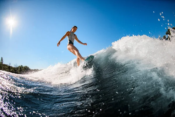 Jovem mulher molhada ativa magistralmente monta a onda na prancha de surf — Fotografia de Stock