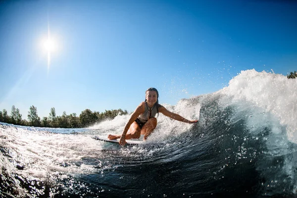 Sorrindo mulher senta-se no wakesurf bordo e monta a onda — Fotografia de Stock