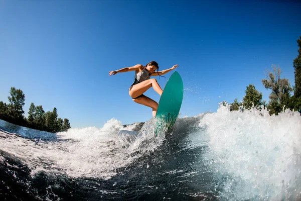 Young wet woman energetically balancing on wave on wakesurf board — Stock Photo, Image