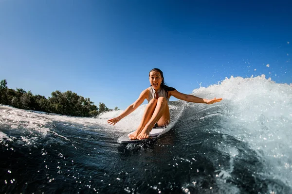 Surpreendentemente alegre mulher senta-se no wakesurf bordo e monta a onda — Fotografia de Stock