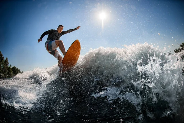 Uomo wakesurfer in gilet da nuoto nero salta con tavola da surf luminoso — Foto Stock