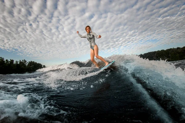 Vista di giovane donna che in piedi su tavola da wakesurf e cavalcando l'onda — Foto Stock