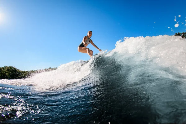 Attiva giovane donna cavalca magistralmente l'onda sulla tavola da surf — Foto Stock