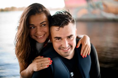 Neşeli kadın portresi ve arka planda mayo giymiş gülümseyen adam.