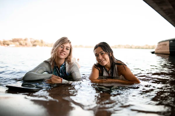 Nehir suyunda sörf tahtası üzerinde yüzen ve kameraya bakan mayo giymiş kadınların görüntüsü — Stok fotoğraf