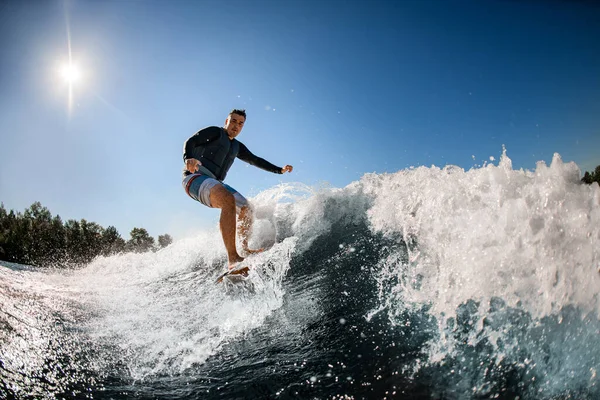 Hombre en chaleco de natación negro monta la ola en la tabla de surf —  Fotos de Stock