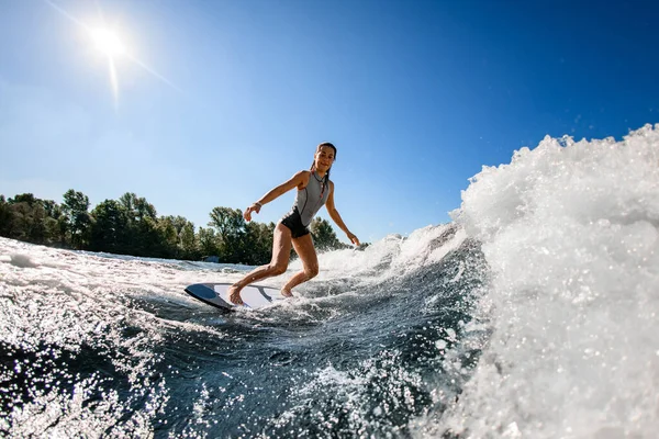 Wakesurfer fêmea em maiô vermelho monta até a onda na prancha de surf — Fotografia de Stock