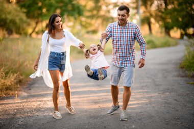Mutlu anne ve baba, çocuğun elini tutun ve onu sallayın.