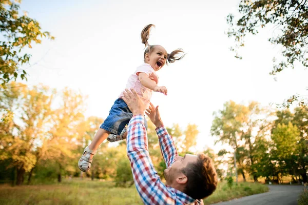 Adorable little girl being thrown up in the air by her father — Stock Photo, Image