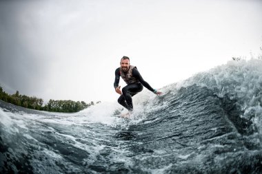 Neşeli adam sörf tahtasına biner dalgalar halinde suya dokunur.