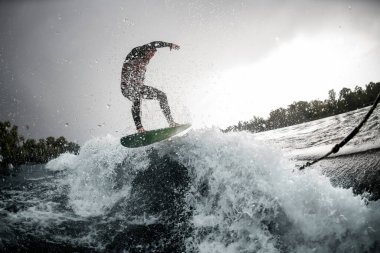 Cesur adam sörf tahtasıyla sahile vuran dalgalar üzerinde süzülüyor..