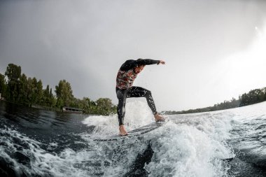 Yakışıklı adam sörf tahtasıyla sahilde dalgalanır.